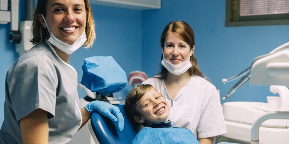 niño y dos dentistas sonriendo